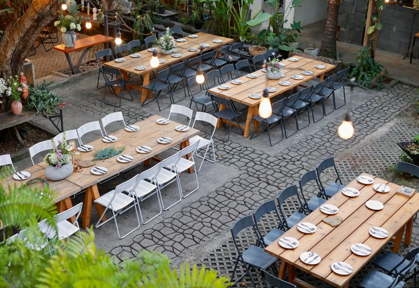Long tables set outdoors under bulb lights at golden hour
