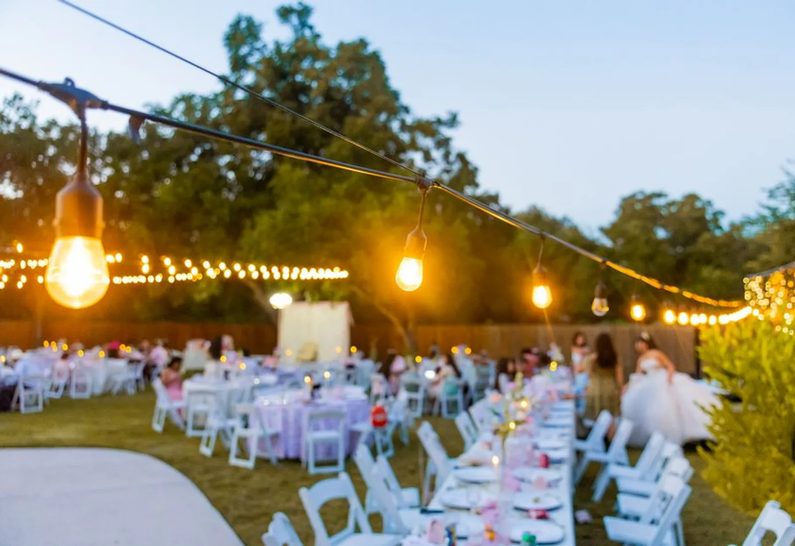 Bulb lights strung above tables just after sunset