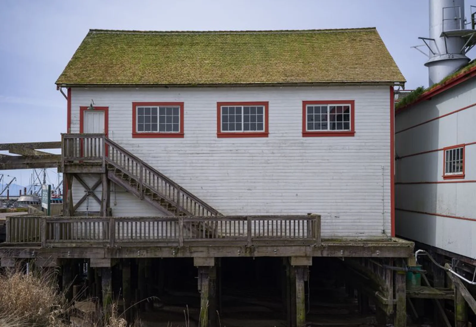 A white clapboard boathouse standing on pilings over the water