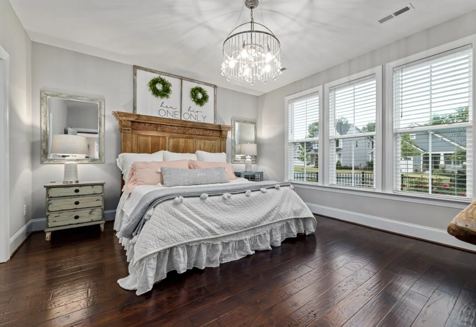 A guest room with a wooden bed and windows on two walls