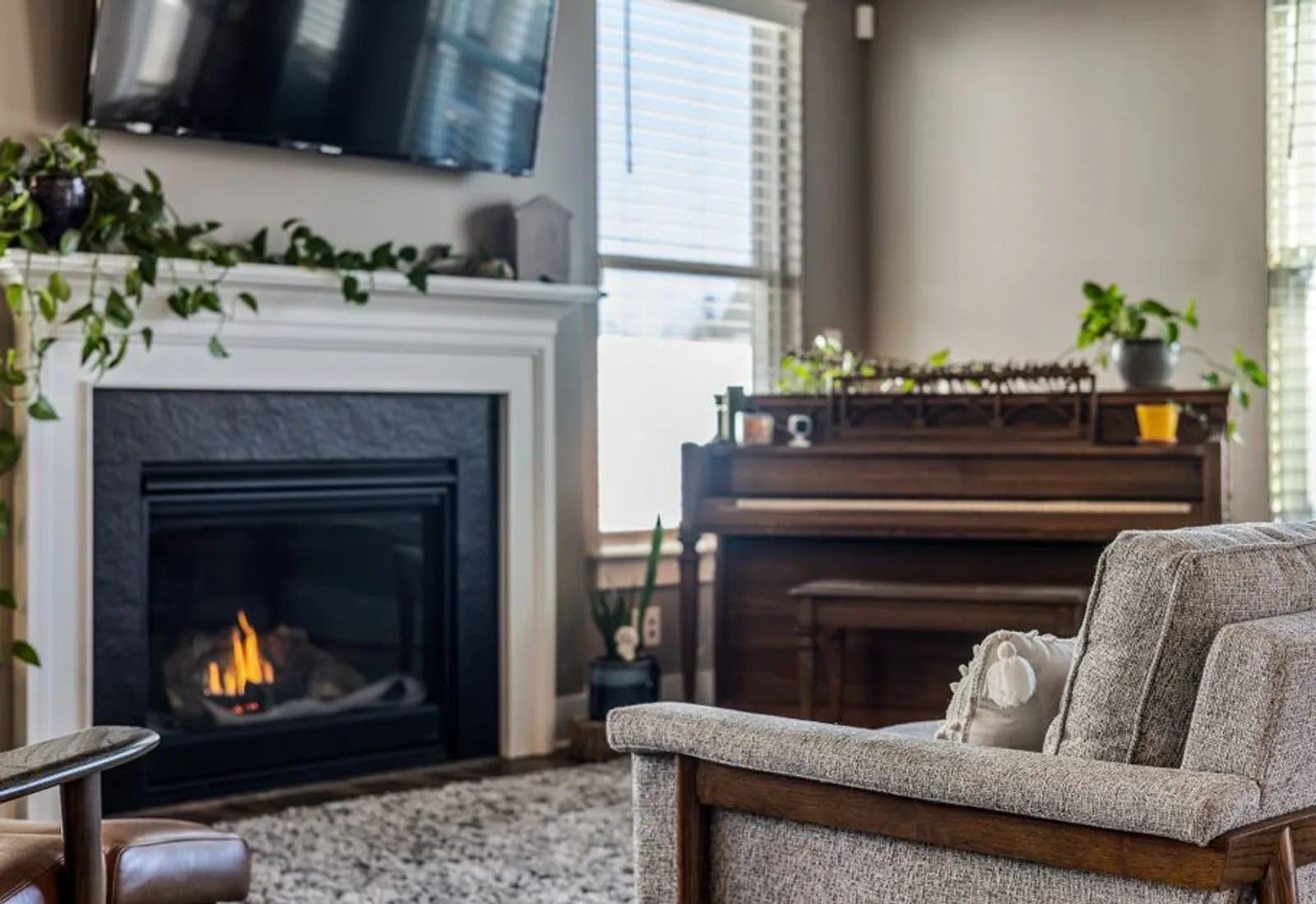 The parlor — a lit fireplace with an upright piano beside it