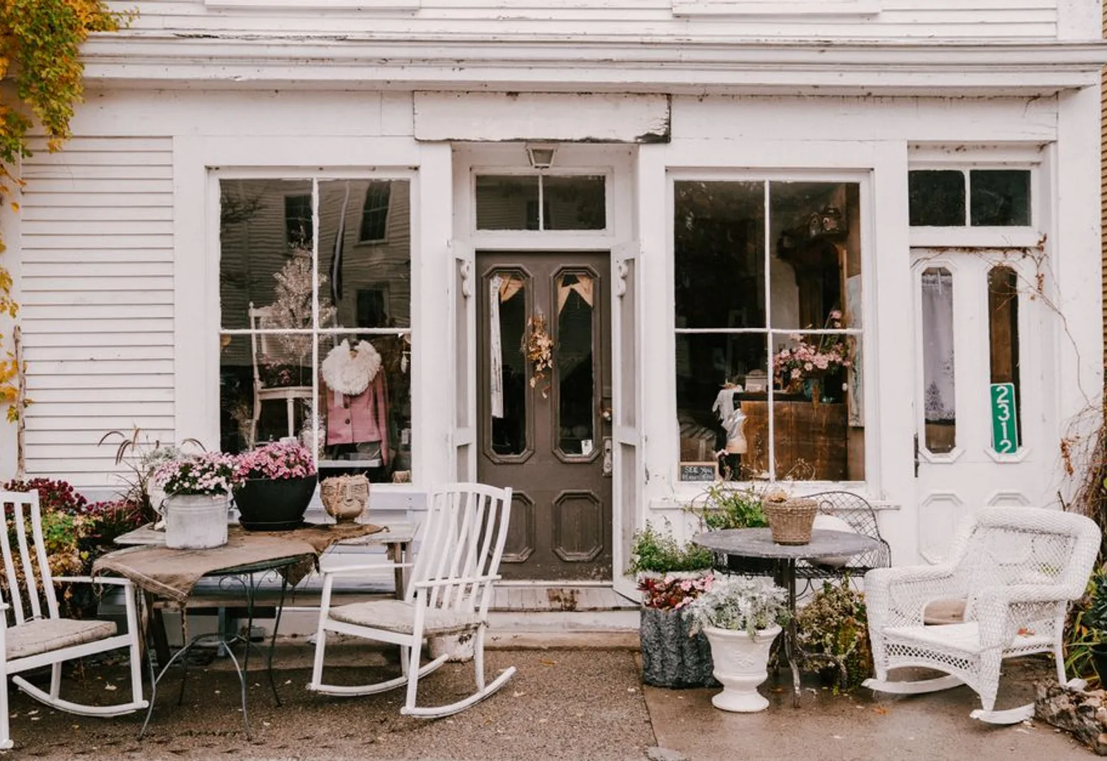 White rocking chairs along a porch lined with flowers