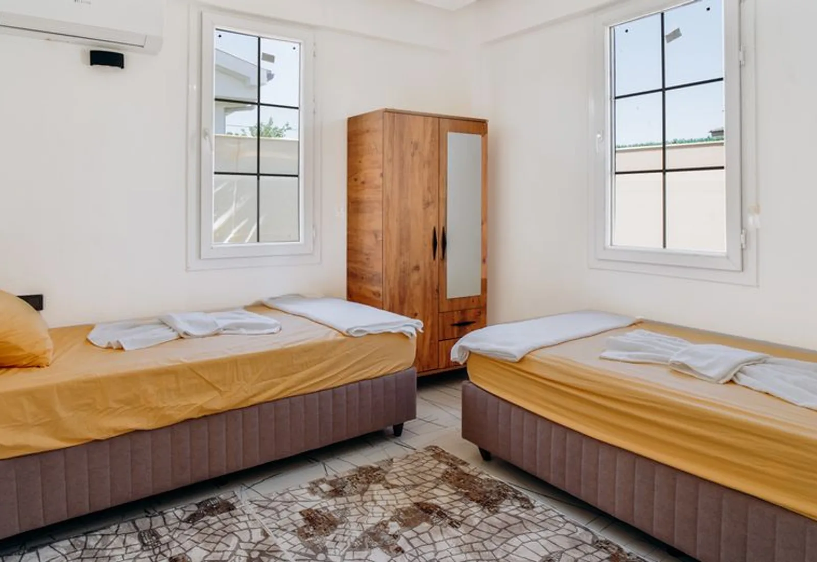 Two twin beds either side of a wardrobe, windows on the garden